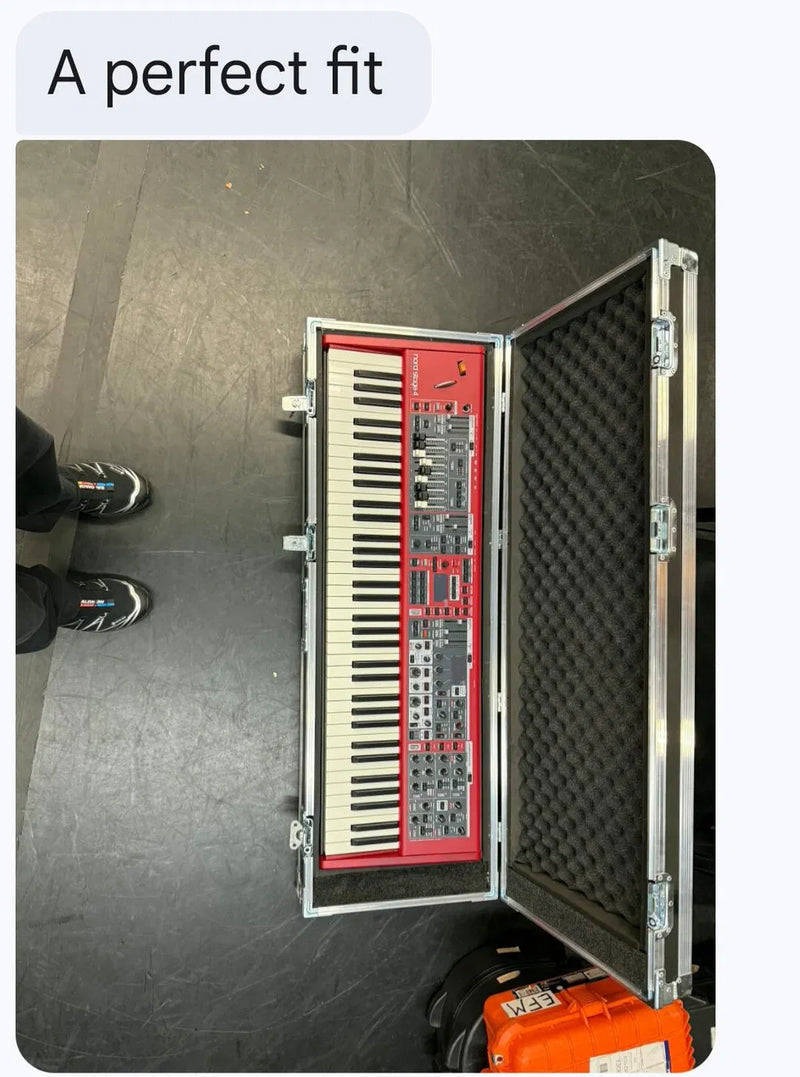A red modular synthesizer keyboard inside an open silver aluminum flight case, shown from a top-down perspective on a dark gray floor.